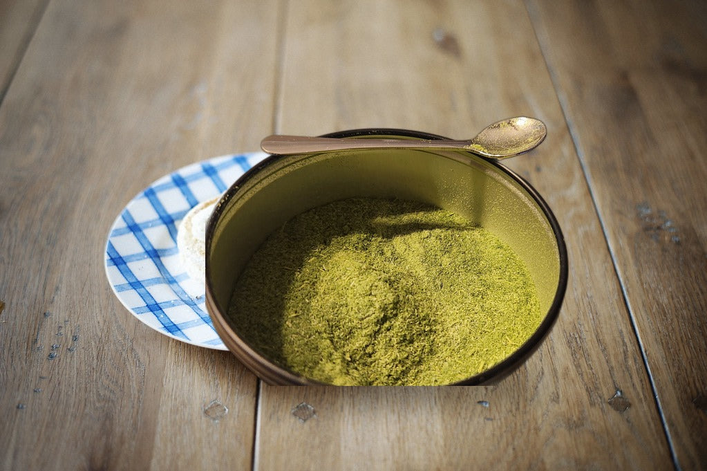 Organic pea microgreen powder in an open tin on a rustic wood table