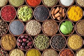 Assorted spices in round containers arranged in a colorful, top-down display