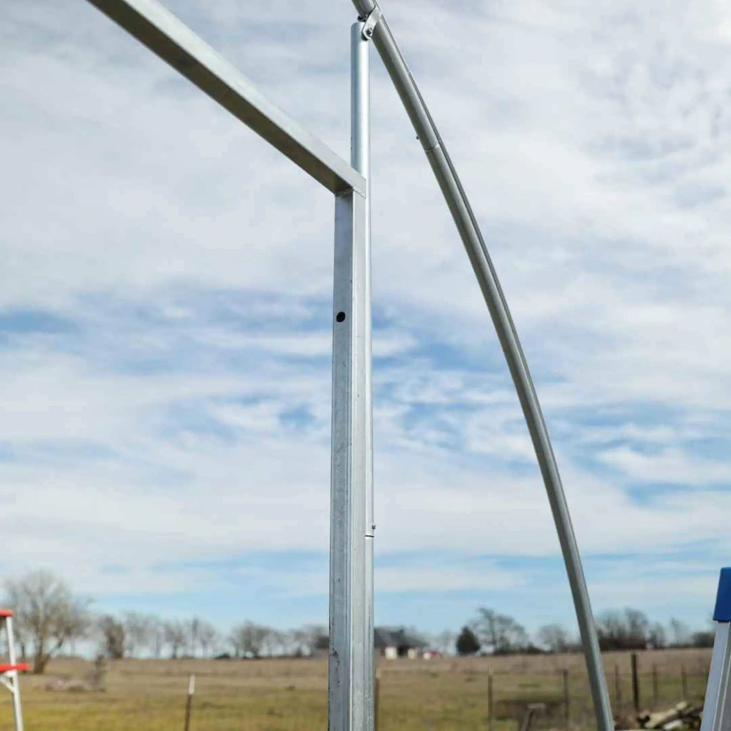 Metal hoop house end wall door frame in open field under blue sky