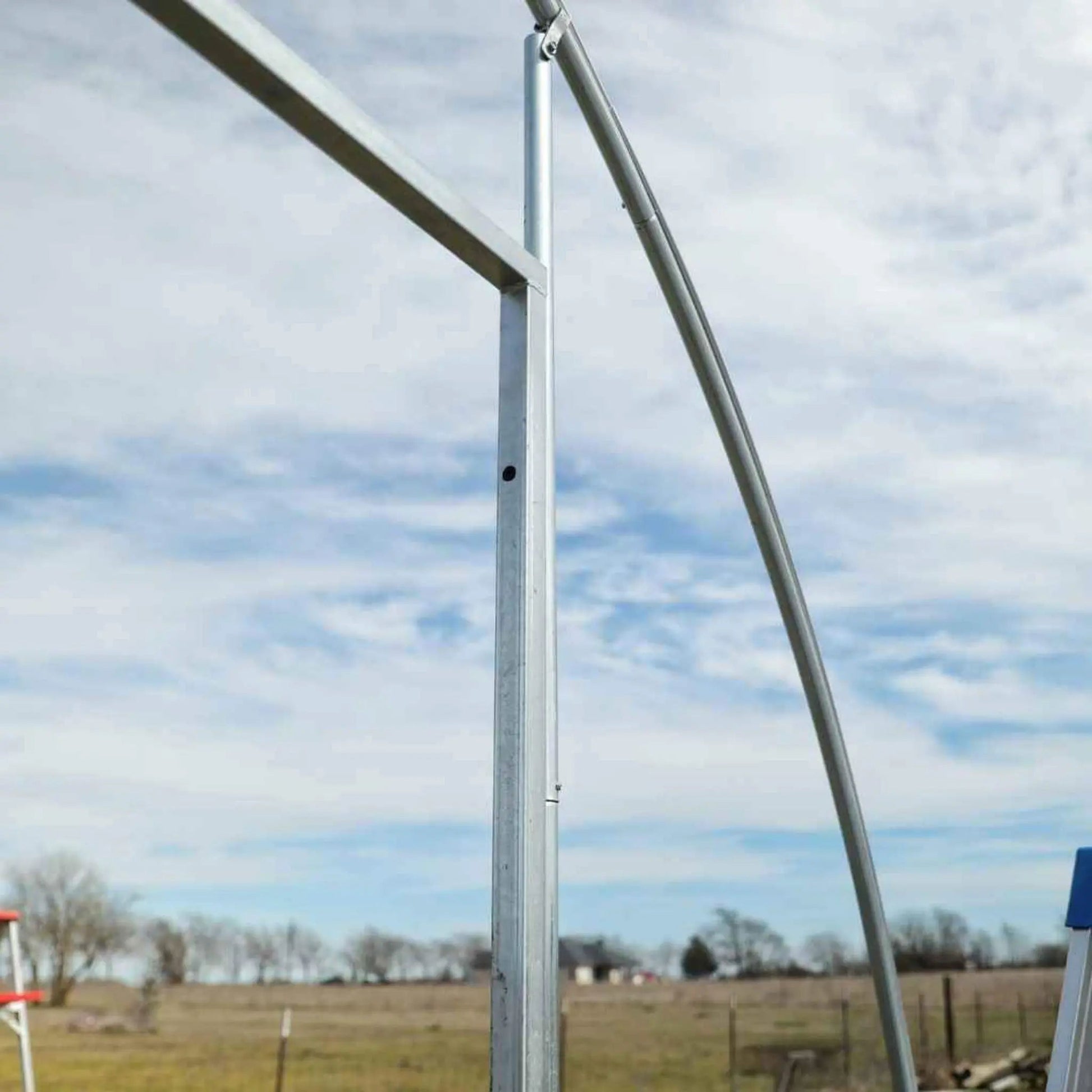 Metal hoop house end wall door frame in open field under blue sky