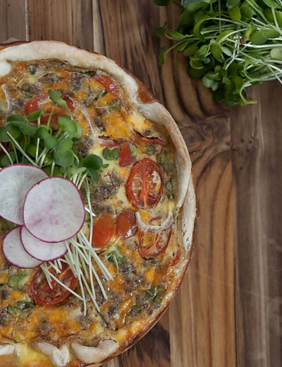 Sausage, tomato, and daikon radish microgreen quiche with sliced radish — a serving idea using Robby Ds Lil Greens organic daikon radish microgreens